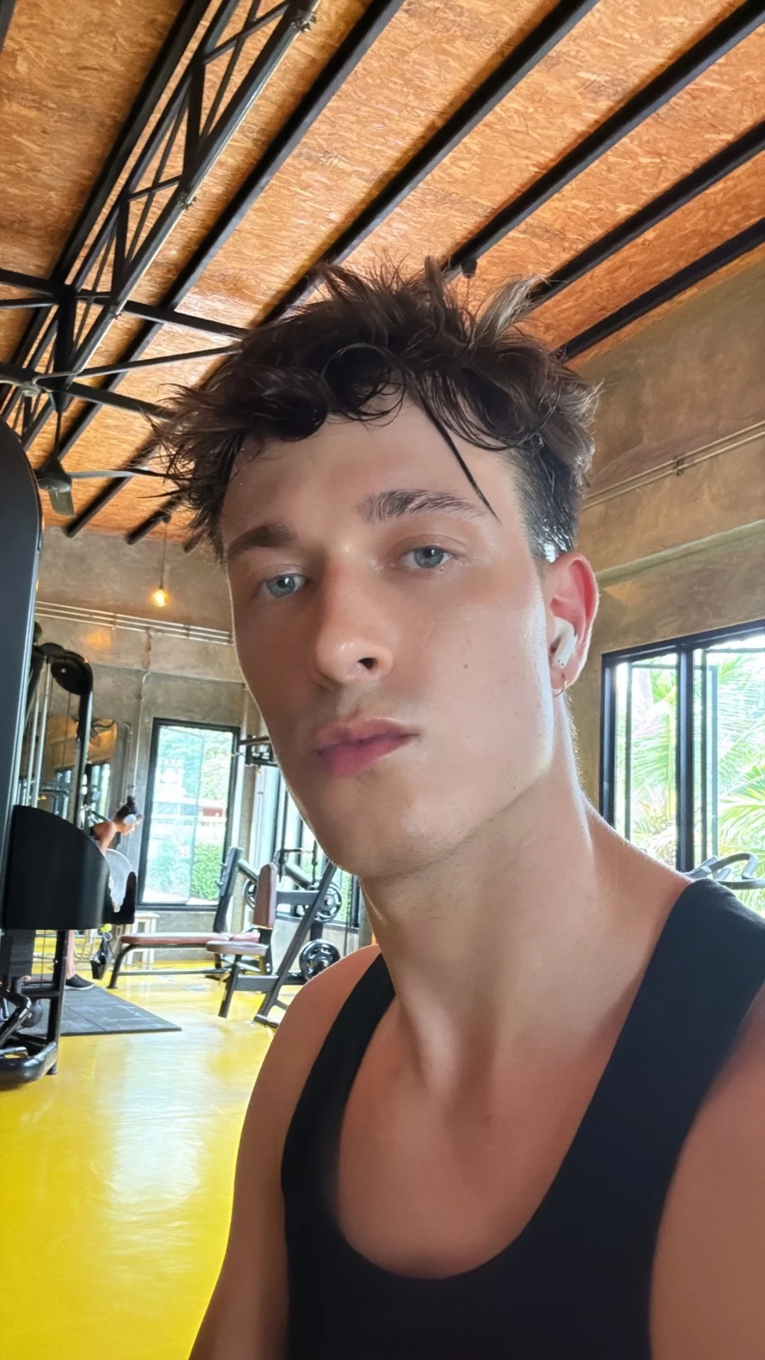 Jules Sauvage, escort gay Paris — moment lifestyle en salle de sport, débardeur noir, instant authentique entre deux séances