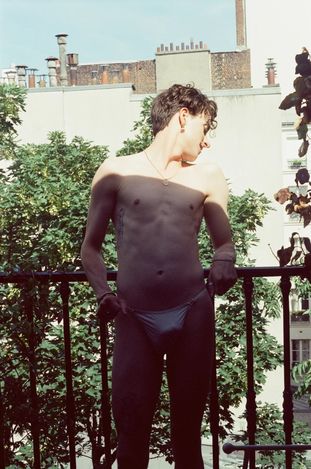Bare chest on a Paris balcony — gay male escort Paris, natural afternoon light