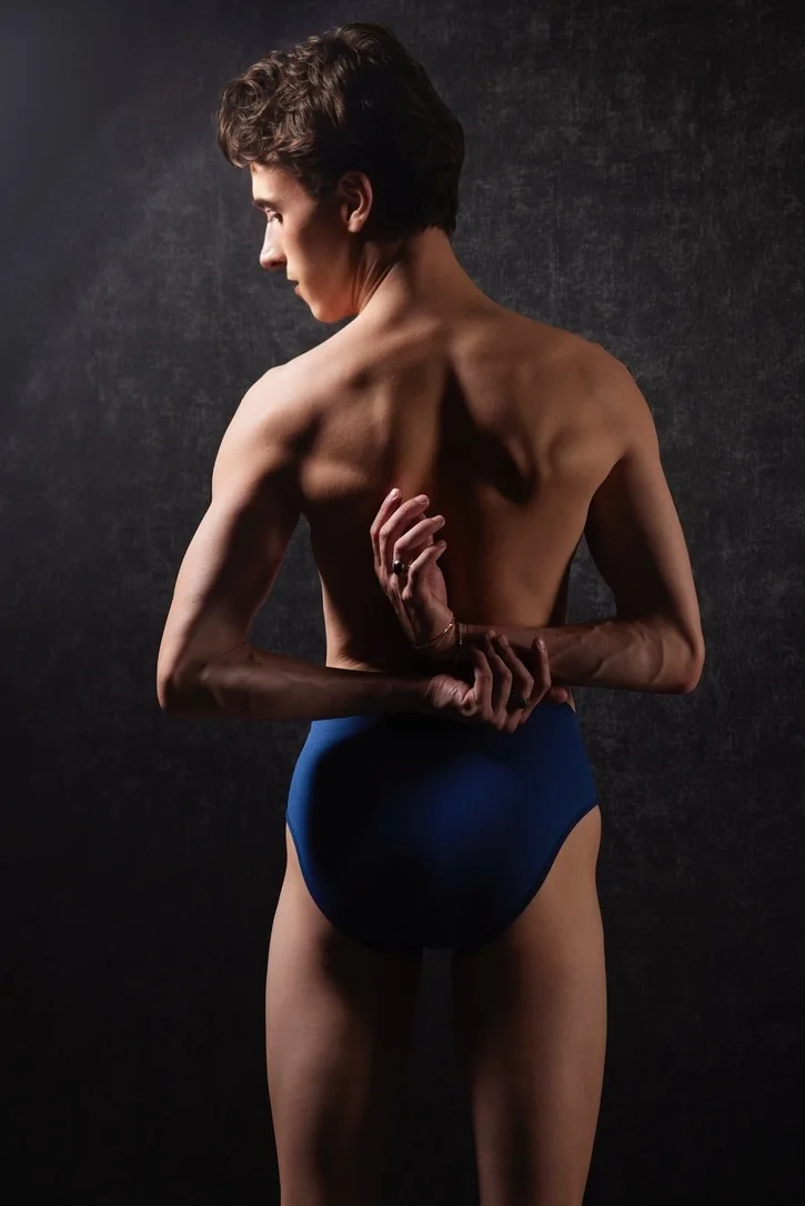 High class gay male escort Paris — studio back portrait, sculpted athletic back, dramatic light